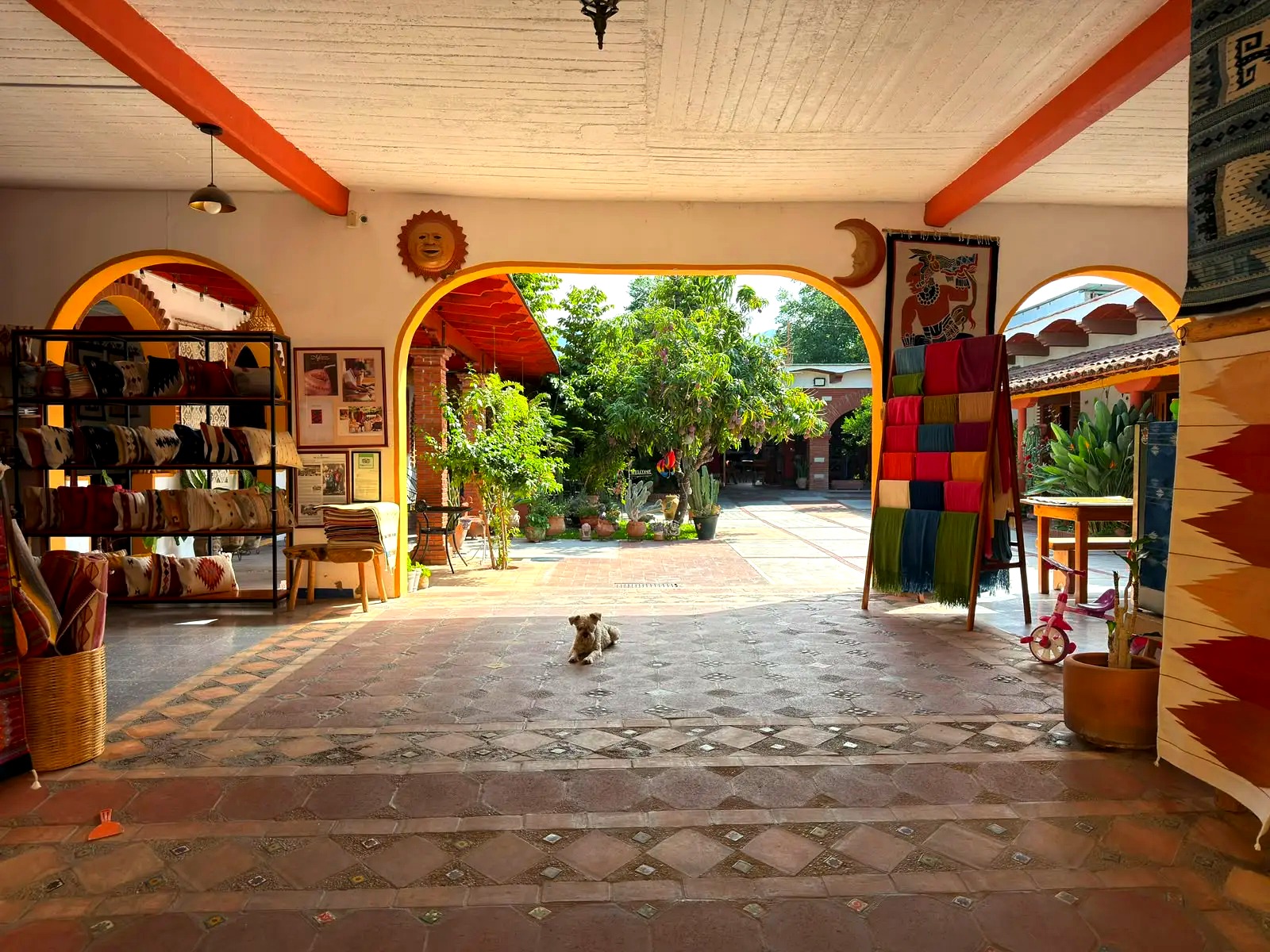 Papel picado overhead, finished tapetes floor to ceiling — every rug woven on-site in Teotitlán del Valle.